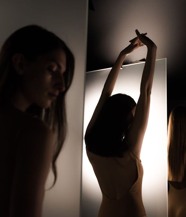 Serene woman in a gentle stretching pose indoors.